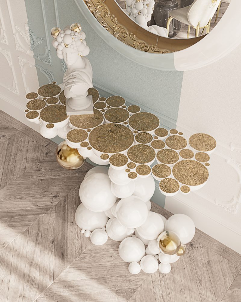 contemporary white console with gold plated accents and a white and gold wall mirror with carved details lined with golden leaf