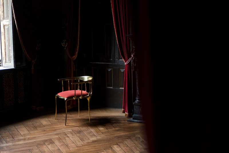 intimate luxury - dark living room, black walls with a window, red curtains and a red and gold chair 