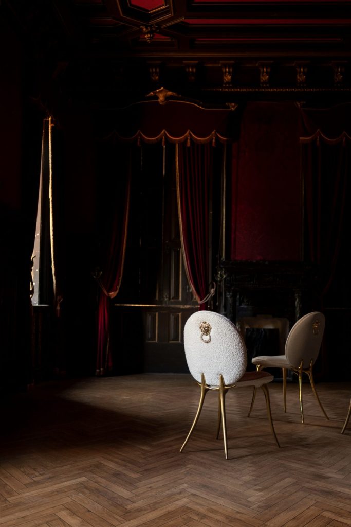 intimate luxury - dark living room with red curtains and cream chair with gold details 