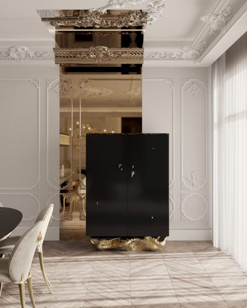 Angra Collection- contemporary dining room, white walls, black table, cream chairs with gold details, white curtains and a black cupboard with gold base  