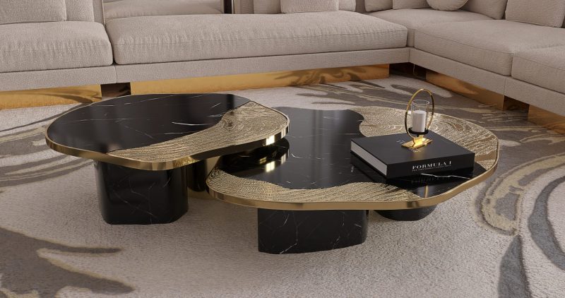 Ophelia Center Table- black coffee table with gold details, a book and a candle, a rug and a cream and gold sofa 