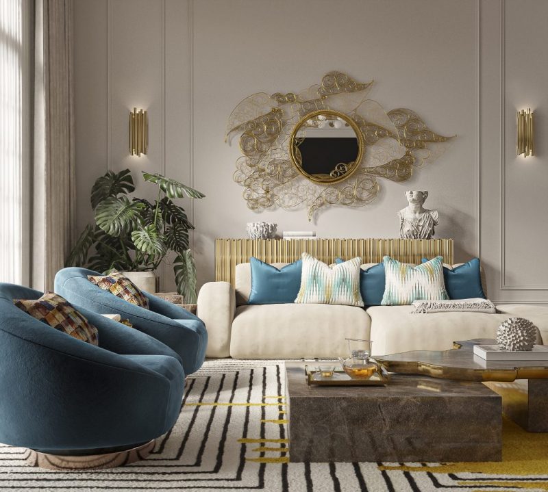 two blue armchairs a nude sofa with blue pillows, symphony sideboard with the filigree mirror on the wall and te navarra center table in emperador marble